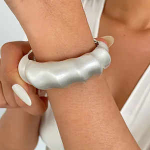 Detailed close-up showing a chunky silver metal bangle with a unique wrinkled texture on wrist