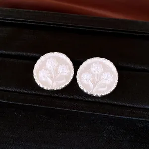 Detailaufnahme von runden Vintage-Ohrsteckern aus Harz mit Blumenmuster und Silberrand