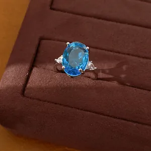 Detailed view of elegant silver ring with oval blue gemstone and white side zircons.