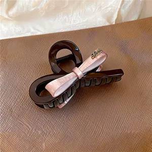 Gros plan sur une pince à cheveux élégante avec nœud en acrylique et détails roses