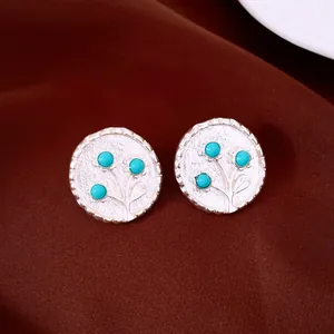 Nahaufnahme von runden silbernen Vintage-Ohrsteckern mit blauen Harzblumen-Details