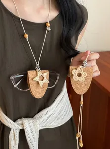 Detailansicht des Kork-Brillenhalters mit geflochtenen Strohsternen und Blumenanhängern.