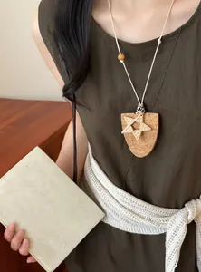 Detailansicht der sternförmigen Kork-Brillenclip-Halskette an einem braunen Kleid