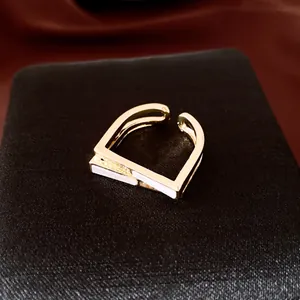 Vue détaillée d'une bague ouverte carrée dorée avec émail blanc et accents de zircons