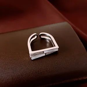 Gros plan d'une bague carrée ouverte en argent avec incrustations de nacre et zircons