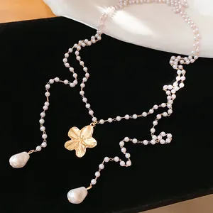 Vue détaillée d'un collier de perles élégant à plusieurs rangs avec un pendentif fleur dorée.
