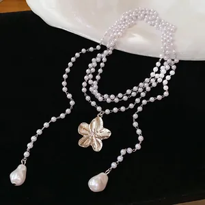 Détail d'un collier multicouche de style français avec un élégant pendentif fleur dorée