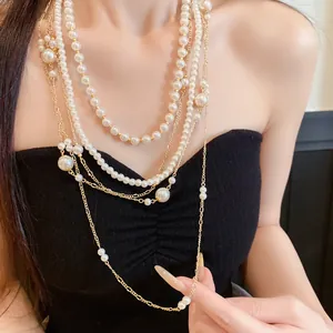 Elegant multi-layered pearl and gold chain necklace shown on a model neck close-up