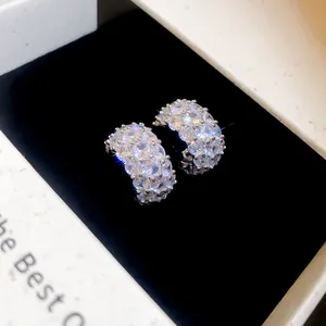 Macro detail of sparkling C-shaped cubic zirconia earrings inside a black velvet box
