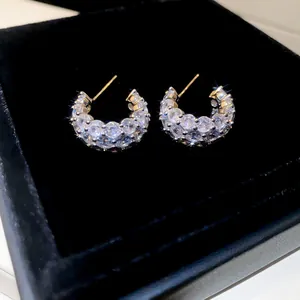 Detailed macro view of sparkling C-shaped cubic zirconia stud earrings in a jewelry box