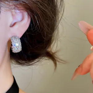Detailed view of sparkling white zircon encrusted C-shaped hoop earrings on model's ear