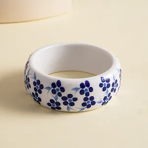 Elegant white resin bangle with blue floral pattern in blue and white porcelain style.