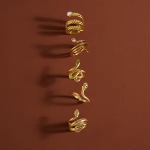 Verticale collectie gouden slangenringen met zirkonia details op bruine achtergrond