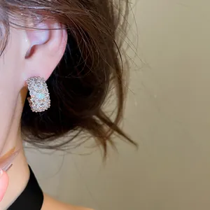 Detailed view of sparkling silver-tone C-shaped earrings with cubic zirconia on model ear