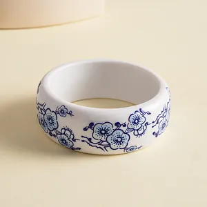 Detailed close-up of a wide resin bangle with blue and white floral porcelain style print