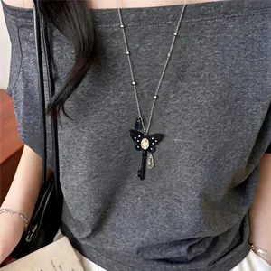 Detailopname van een Franse vlindersleutel hanger ketting gedragen door een vrouwelijk model.