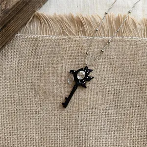 Detailweergave van een vintage ketting met zwarte sleutelhanger en glanzende strass.