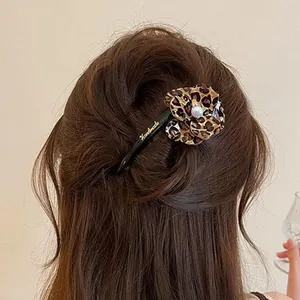 Elegant leopard print flower twist hair clip shown on the back of brown wavy hair
