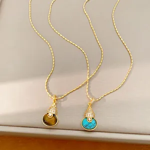 Detailopname van 18k vergulde kalebas kettingen met tijgeroog en turquoise stenen
