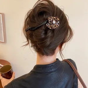 Close-up view of a leopard print flower hair clip styled on a brown hair bun updo