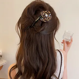 Back view of an elegant leopard print flower hair clip styled in long wavy brown hair.