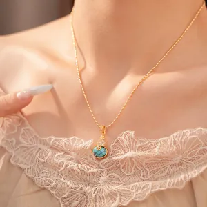 Detailweergave van 18k vergulde kalebas hanger ketting met turquoise steen en zirkoon accenten.
