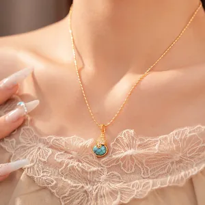 Detailopname van 18k vergulde kalebas ketting met turkoois en zirkoniasteen