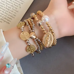 Close-up of four-piece beaded bracelet set with religious coins and heart pendants