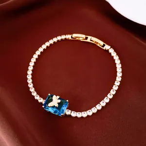 Close-up detail of 18k gold plated bracelet featuring a blue square crystal and butterfly motif.