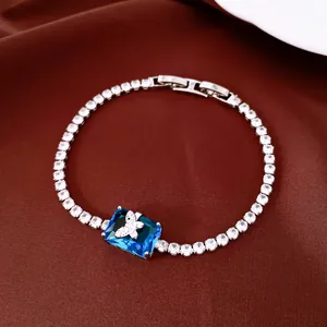 Detail of 18k gold plated tennis bracelet with butterfly and blue gemstone centerpiece