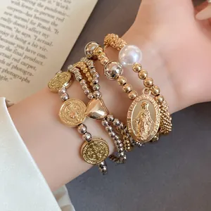 Macro view of four-piece elastic beaded bracelet set featuring heart and religious charms
