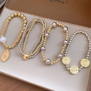 Detailed shot of 4-piece stretch beaded bracelet set with saint coin and heart pendants