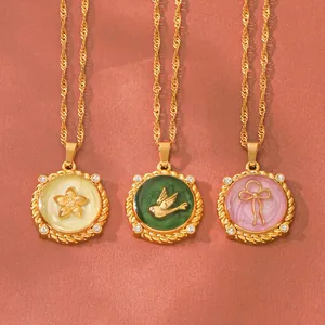 Close-up of enamel round pendants with flower bird and bow designs on gold chains