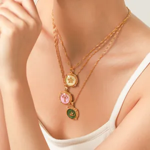 Detail of triple layered gold-finish necklaces with colorful enamel pendants on model
