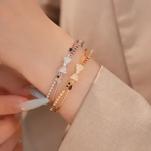 Detailansicht von geschichteten Zirkon-Schleifen-Armreifen in Gold und Silber am Handgelenk