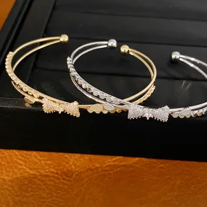 Nahaufnahme eleganter zweilagiger Armreifen mit funkelnden Zirkon-Schleifendetails.