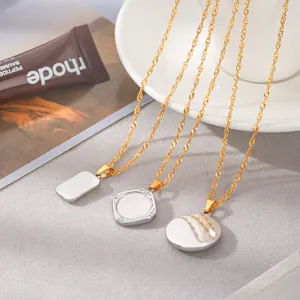 Détail de chaînes à vagues dorées avec des pendentifs blancs laqués au design épuré
