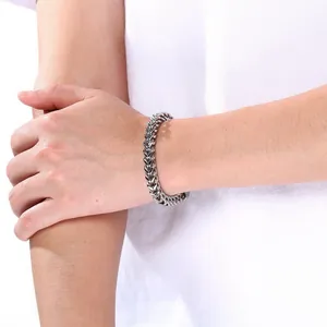 Detailed view of a silver stainless steel dragon bone wheat chain bracelet on a man's wrist