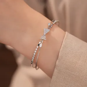 Elegantes Detail eines silbernen Armreifs mit funkelnder Zirkon-Schleife am Handgelenk