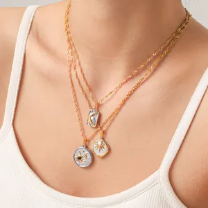 Détail de trois colliers superposés en or 18 carats avec pendentifs soleil et lune émaillés