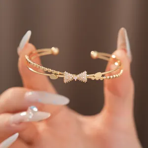Detaillierte Makroansicht eines vergoldeten Armreifs mit Zirkonia-Schleifen-Design.