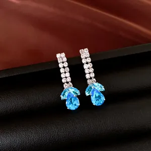 Détail de boucles d'oreilles pendantes goutte d'eau bleue avec clous en strass blanc étincelant