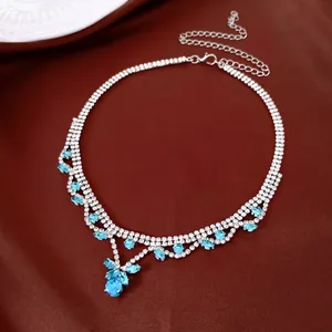 Détail d'un collier argenté orné de cristaux bleus étincelants en forme de goutte d'eau