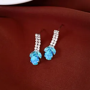 Gros plan d'élégantes boucles d'oreilles pendantes en zircone goutte d'eau bleue