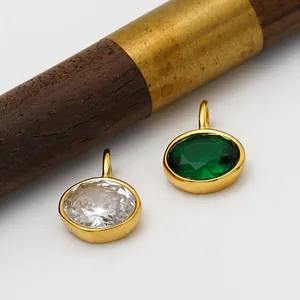 Gros plan de pendentifs ovales en acier inoxydable avec zircons émeraude et blancs.