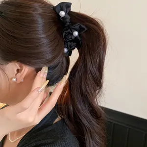 Elegante schwarze Stoff-Schleifen-Haarspange mit weißen Perlen in einem Pferdeschwanz