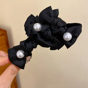 Nahaufnahme einer eleganten schwarzen Stoff-Haarschleife mit dekorativen weißen Acrylperlen