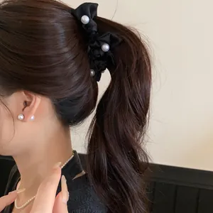 Nahaufnahme einer eleganten schwarzen Haarschleife mit Perlen in einem Pferdeschwanz.