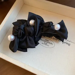 Detailansicht einer eleganten schwarzen Haarklammer aus Stoff mit weißen Perlen