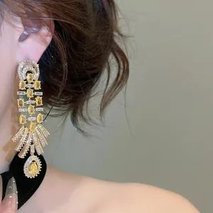Detail of vintage luxury 18k gold plated earrings with yellow teardrop zircons.